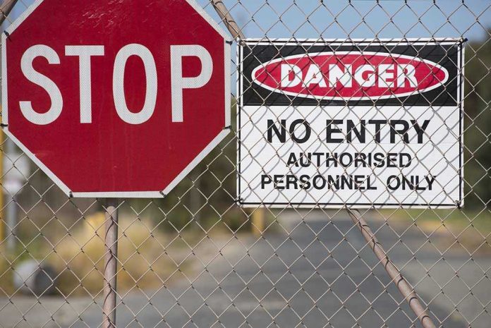 Stop and Danger signs on a chain-link fence.