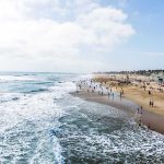 Crowded beach with waves and people enjoying sun.