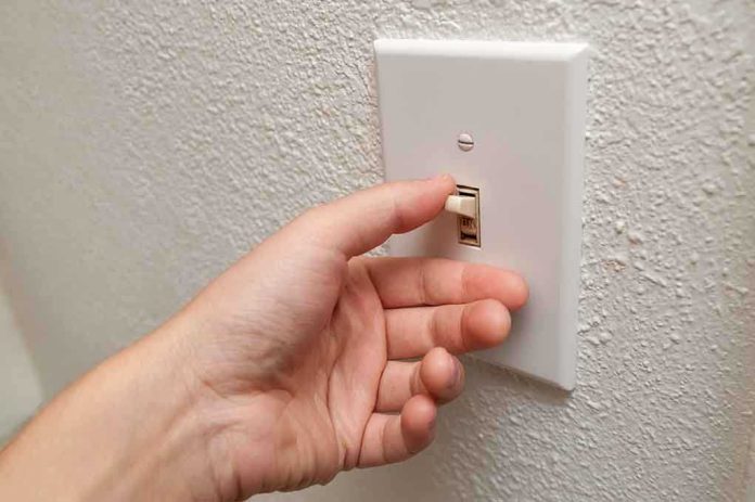 A hand reaching to turn on a light switch on a textured wall
