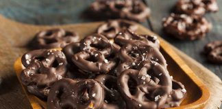 A wooden bowl filled with chocolate-covered pretzels sprinkled with sea salt