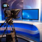 Chilling TV Interview Triggers Police Red Flags TV studio with camera and empty anchor desk.