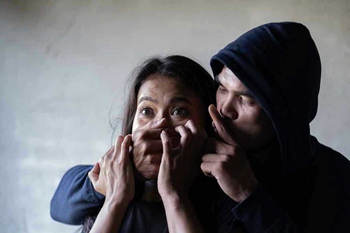 1381990856 Man holding womans mouth, gesturing silence.