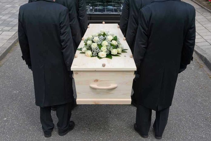 144558722 Four people carrying a coffin with white flowers.
