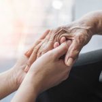 Young hands holding an elderly persons hand.