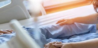 Hospital patient holding visitors hand reassuringly.