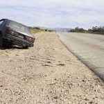 Abandoned car on the side of a deserted road in a dry landscape