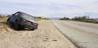 Abandoned car on the side of a deserted road in a dry landscape