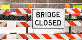 A Bridge Closed sign surrounded by safety barriers and fencing