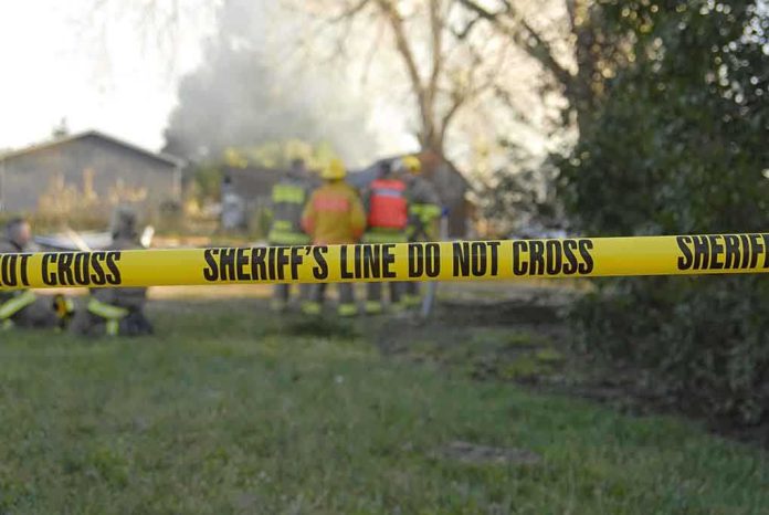 shutterstock_5838397.jpg Yellow police tape marking a restricted area at a fire scene with firefighters in the background