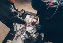 Two individuals handling stacks of money on a table.