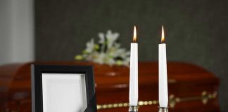 Casket, photo frame, and two lit candles.