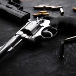 11-Year-Old SHOOTS Mother’s Attacker Revolvers and bullets on a dark surface.