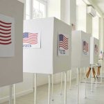 Voting booths with American flag and VOTE signs.
