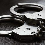 Close-up of metal handcuffs on a dark surface.