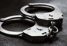 Close-up of metal handcuffs on a dark surface.