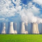 Nuclear power plant with cooling towers emitting steam against a blue sky