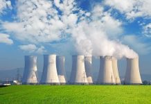 Nuclear power plant with cooling towers emitting steam against a blue sky