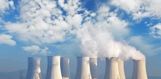 Nuclear power plant with cooling towers emitting steam against a blue sky