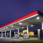 A gas station at night with illuminated fuel pumps and a convenience store