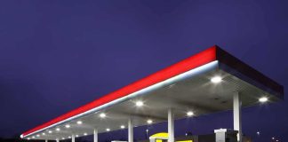 A gas station at night with illuminated fuel pumps and a convenience store