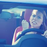 Angry woman gripping the steering wheel in a car