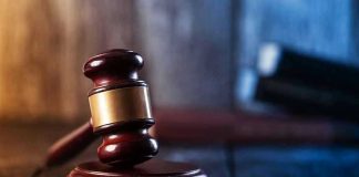 Gavel on wooden table in dimly lit room.