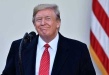 Man in suit and tie speaking at podium.