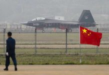 Jet with 31001 marking behind barbed wire fence.