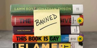 Stack of banned books with a sticky note.