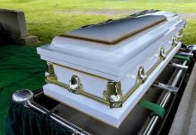 White casket on a lowering device at gravesite.
