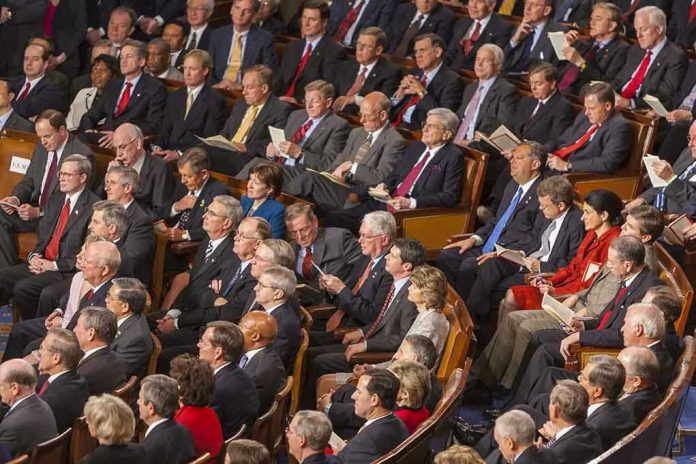 Audience of officials sitting and reading documents in auditorium.