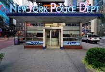 NYPD precinct building with signs on a city street