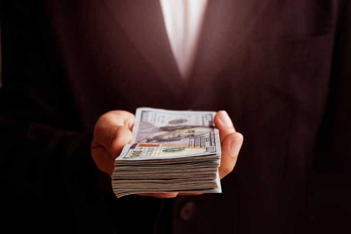 Hand holding a stack of hundred-dollar bills.