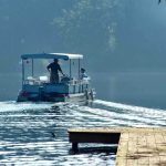 Two people on a boat navigating a misty lake