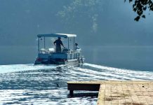 Two people on a boat navigating a misty lake