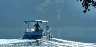 Two people on a boat navigating a misty lake