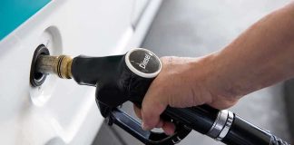 A hand holding a diesel fuel nozzle while refueling a vehicle