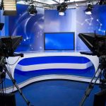 A television studio setup with cameras and a blue backdrop