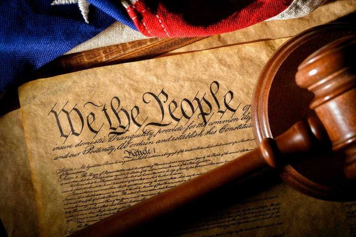 1650343750-1 Gavel on U.S. Constitution with flag backdrop.