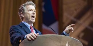 Tucker Denies 2028 Run But Critiques System A politician delivering a speech at a conference podium