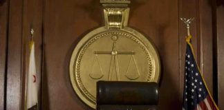 A judges bench in a courtroom with a gavel and flags