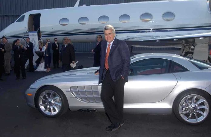 shutterstock_96916091 A man in a suit poses next to a silver luxury car in front of a private jet