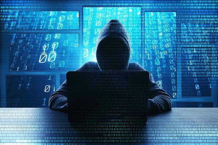 Person in hoodie using a laptop with digital code.