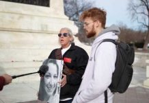 Murder Turned Content — Who Owns Tragedy? Two individuals at a protest, one holding a portrait of a woman