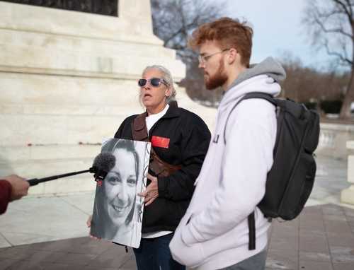 shutterstock_2102154604-1- Two individuals at a protest, one holding a portrait of a woman