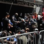 Police Commissioner Torches Pride Ban A group of people interacting with police officers in an urban environment