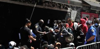 Police Commissioner Torches Pride Ban A group of people interacting with police officers in an urban environment