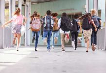 Children running with backpacks outside a school building.