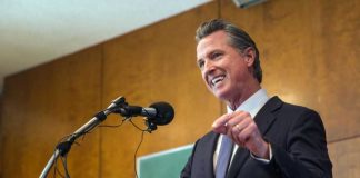 Pay Grab Frenzy Hits California Schools A man in a suit delivering a speech at a podium with microphones