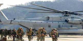 Iran Strike Kills Americans Soldiers disembark and walk past a large military helicopter